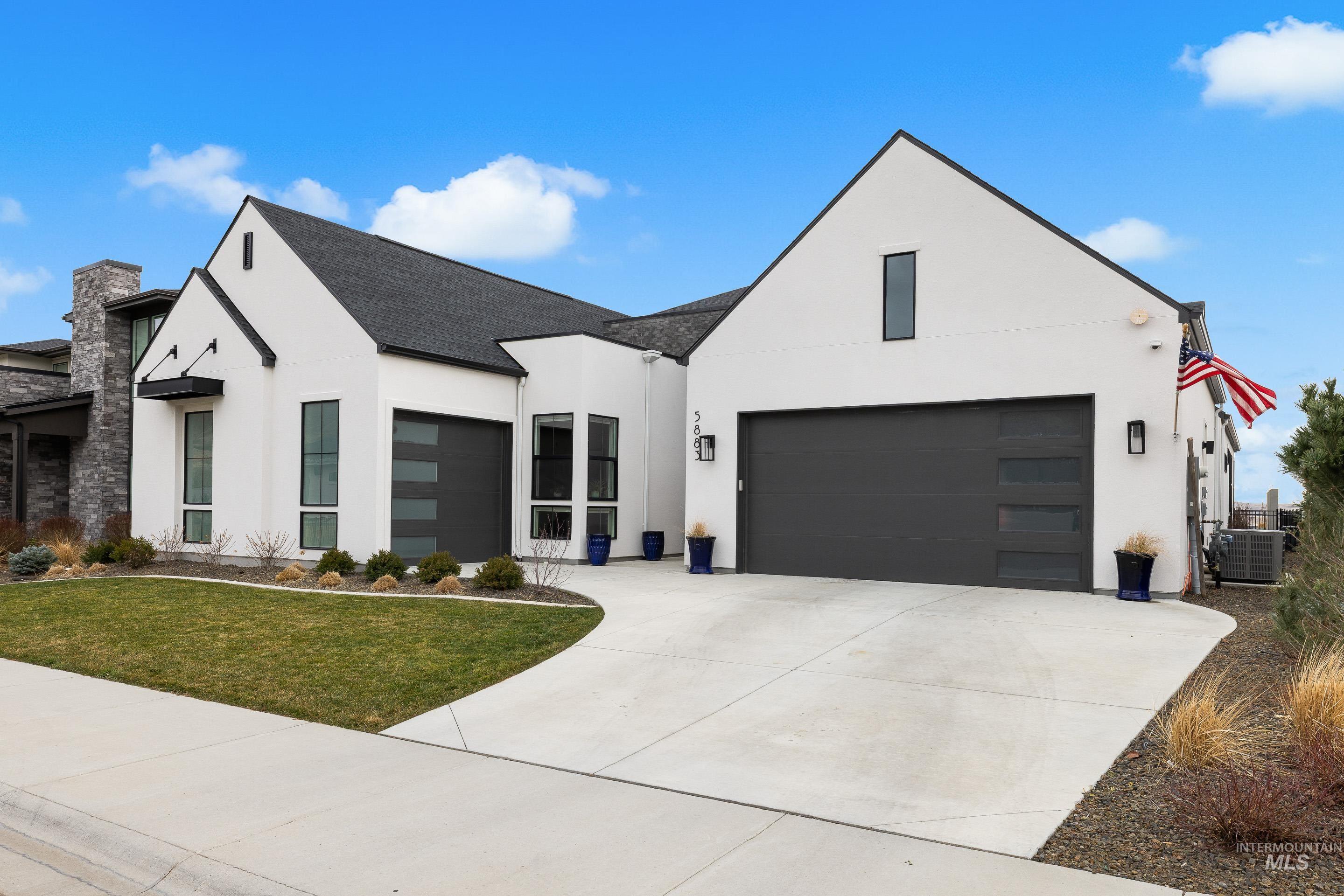 View of front of property with stucco siding, driveway, a front yard, a shingled roof, and a garage