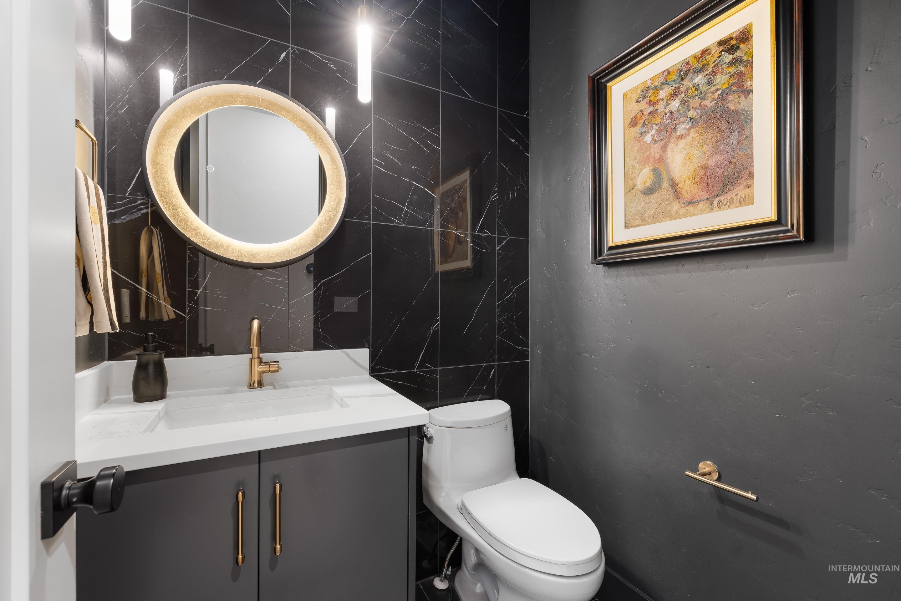 Half bathroom featuring vanity and tile walls