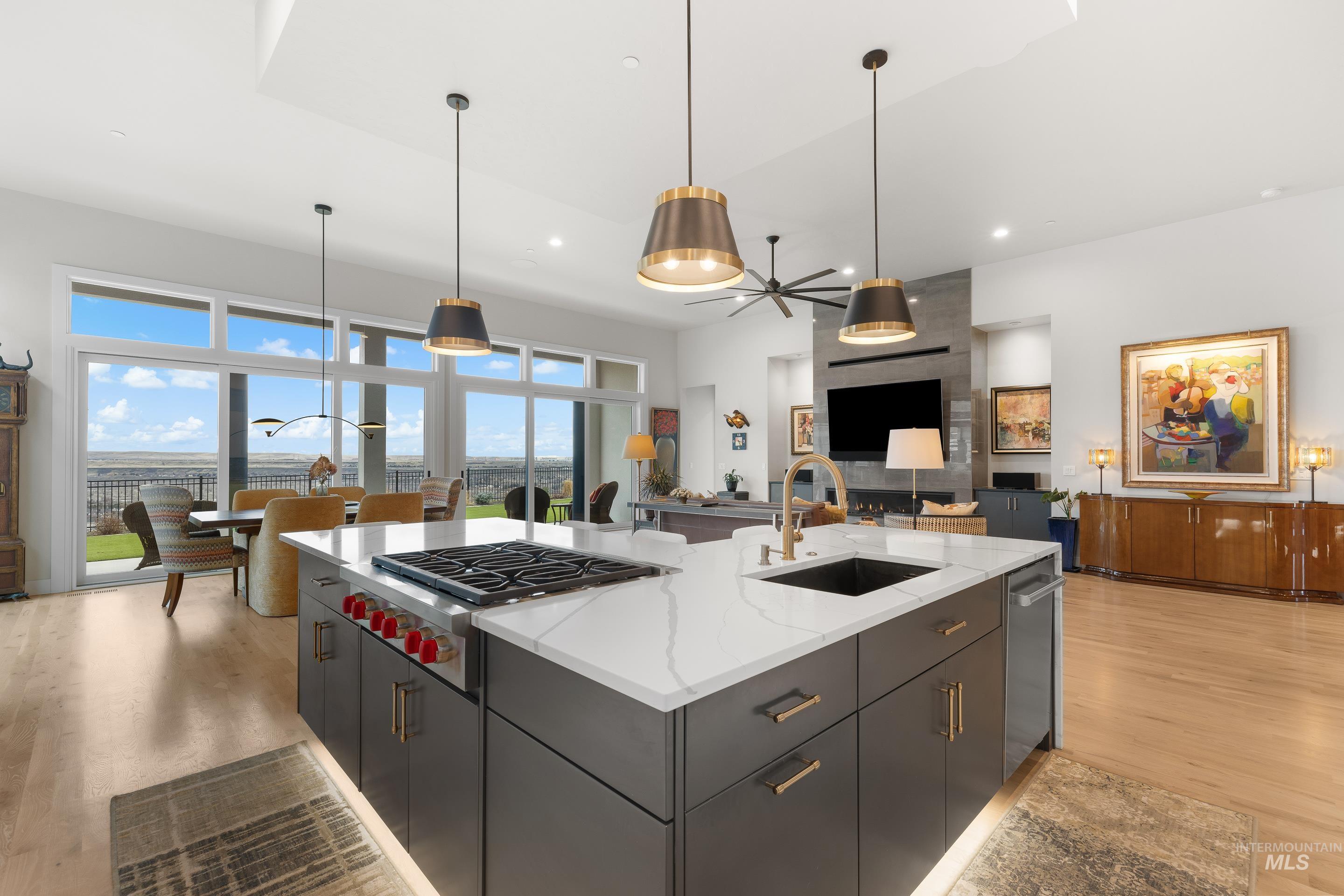 Kitchen with light wood-style floors, hanging light fixtures, and a kitchen island with sink