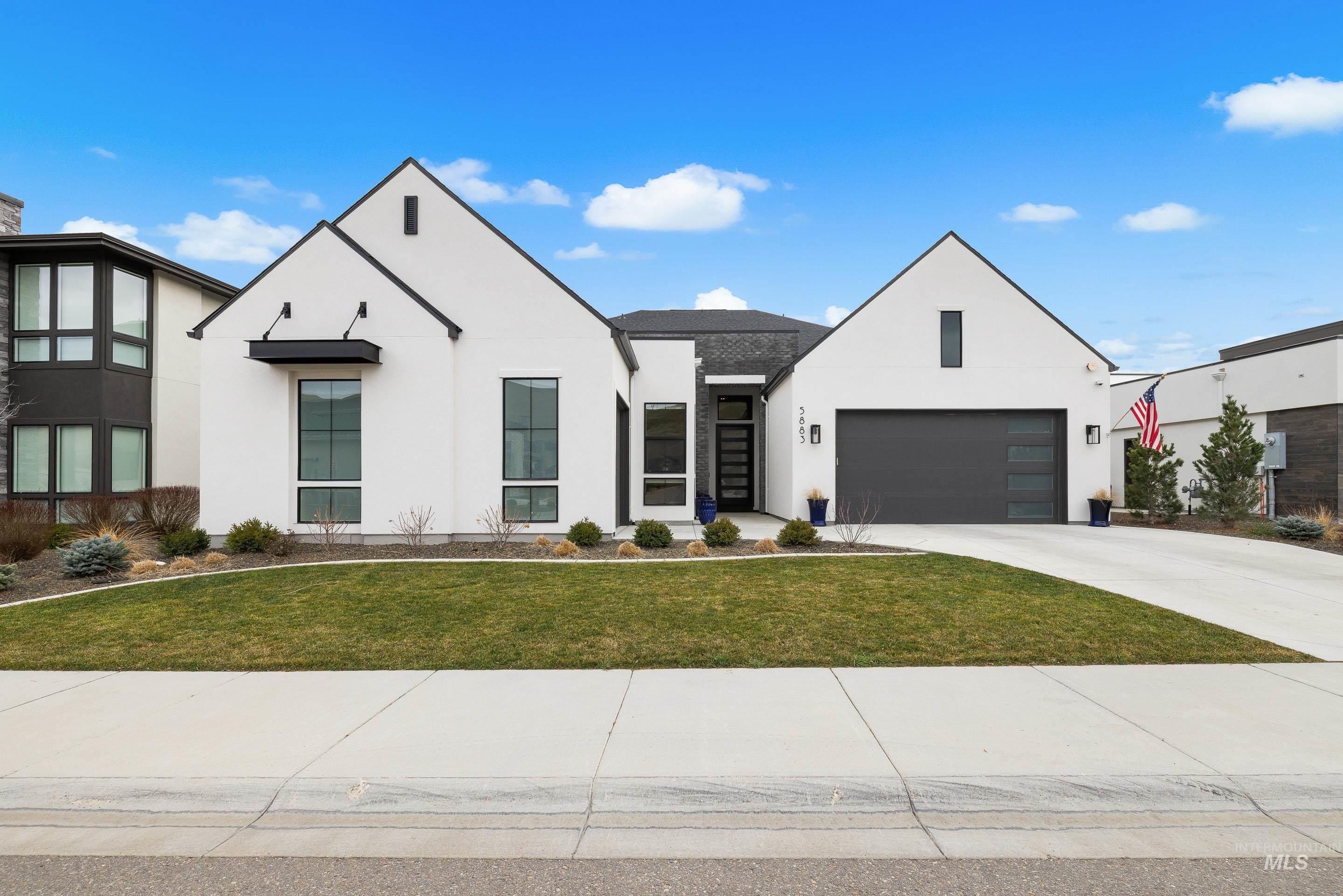 Modern inspired farmhouse with stucco siding, driveway, and a front lawn