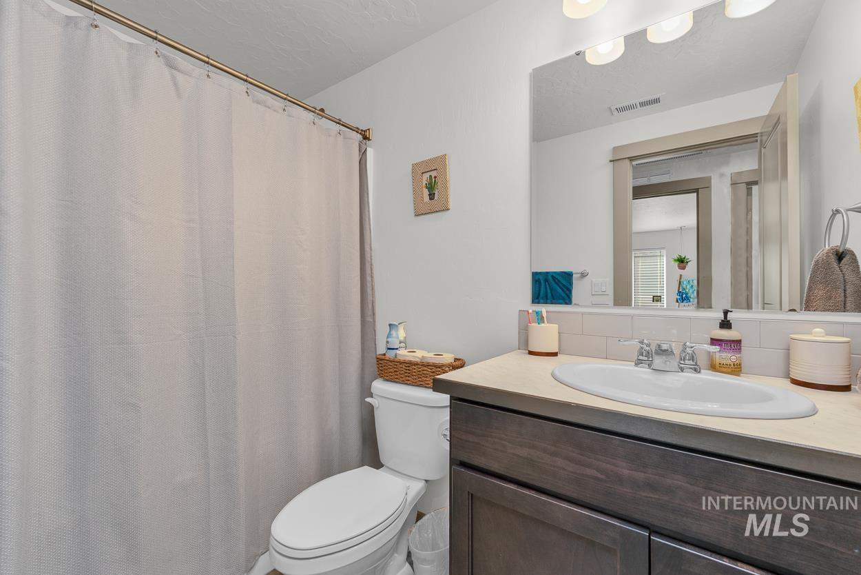 Full bath with vanity, decorative backsplash, a shower with shower curtain, and a textured ceiling