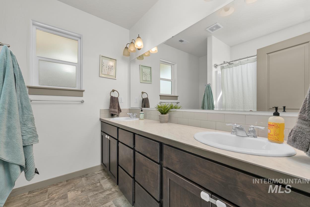 Full bathroom with double vanity, stone finish flooring, and a shower with curtain