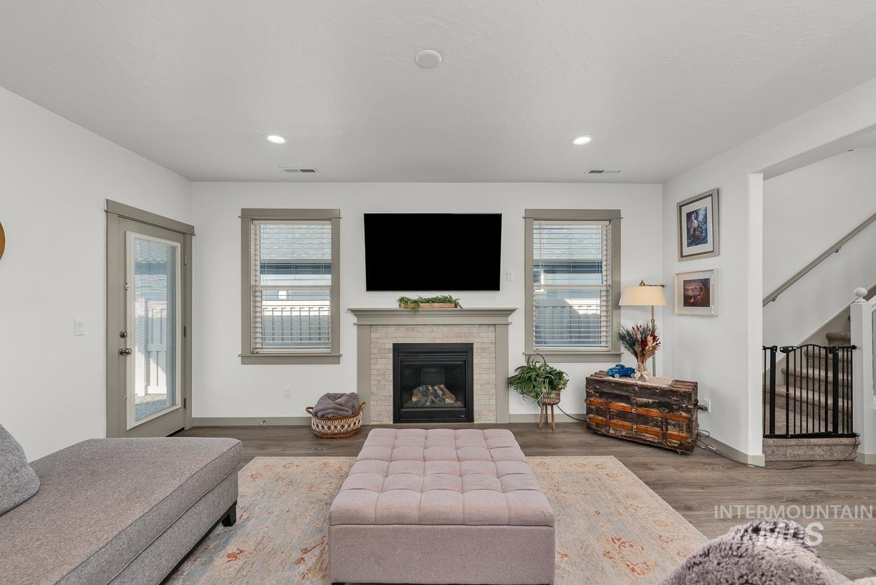 Living area featuring a brick fireplace, wood finished floors, recessed lighting, and stairs