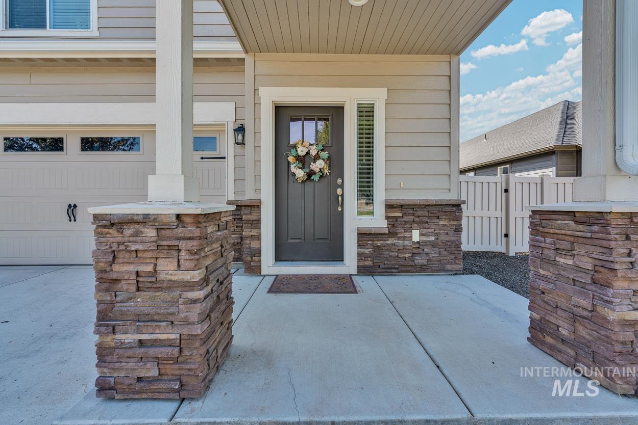 Property entrance featuring a porch, stone siding, and a patio