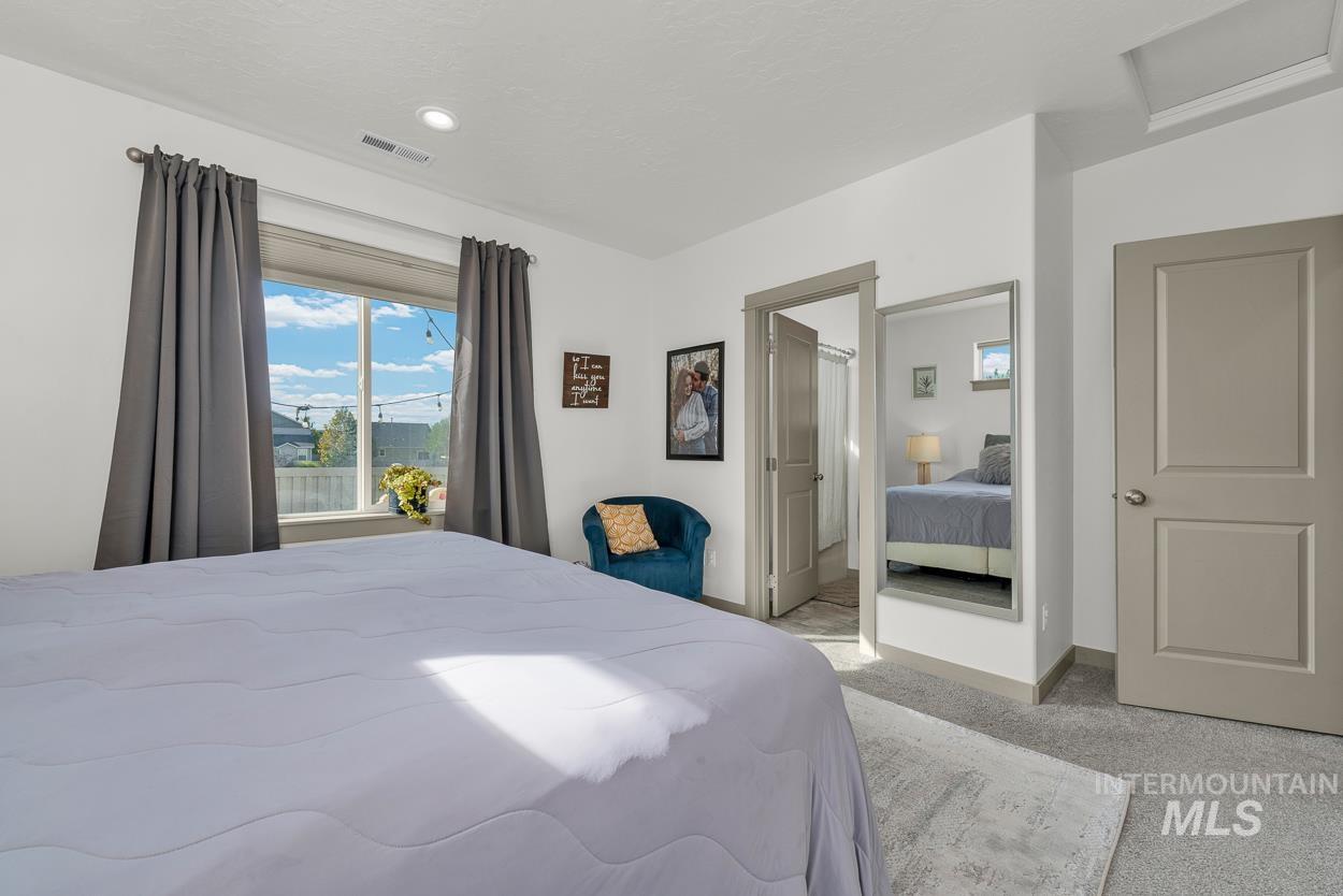 Bedroom featuring light carpet, ensuite bath, attic access, and recessed lighting