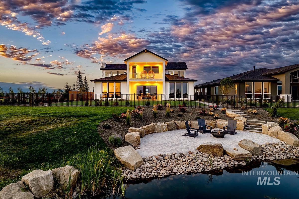 Back of house at dusk with a fire pit, a patio, a fenced backyard, and a balcony