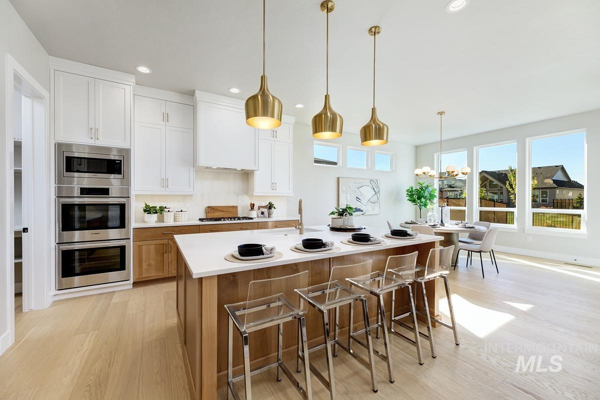 Kitchen featuring brown cabinets, white cabinetry, a breakfast bar, light wood-style floors, and recessed lighting