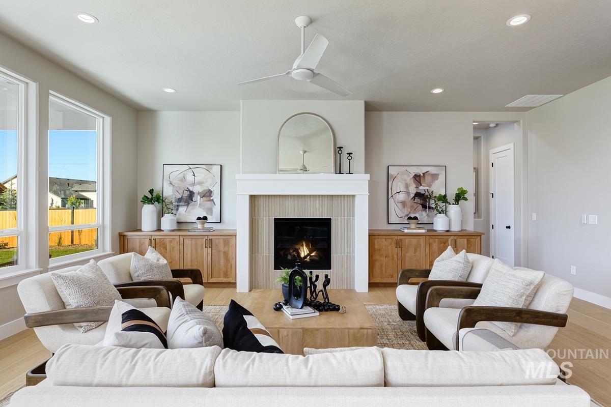 Living room with light wood finished floors, a fireplace, recessed lighting, and ceiling fan