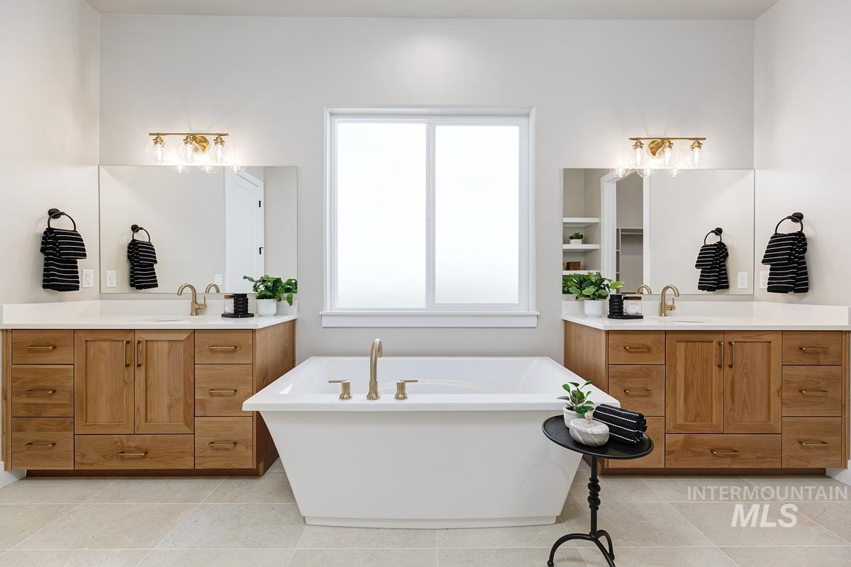 Bathroom with two vanities, a freestanding bath, and light tile patterned floors