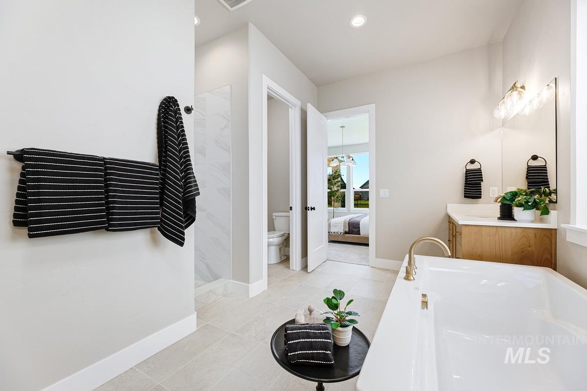 Ensuite bathroom with vanity, walk in shower, a garden tub, light tile patterned floors, and recessed lighting