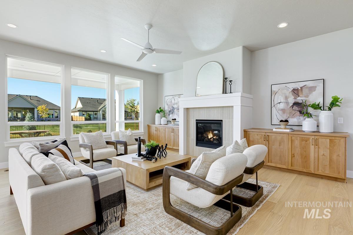 Living area featuring light wood-style flooring, a tiled fireplace, recessed lighting, and a ceiling fan