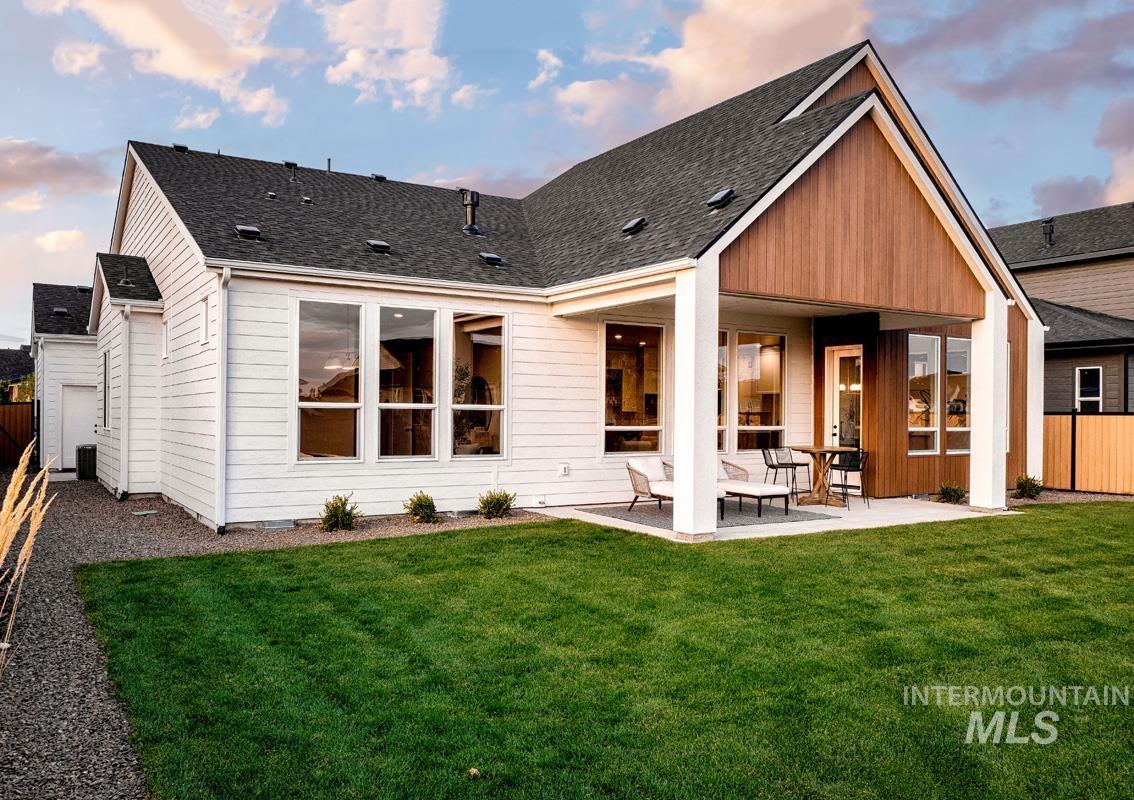 Back of property featuring a fenced backyard, roof with shingles, and a patio