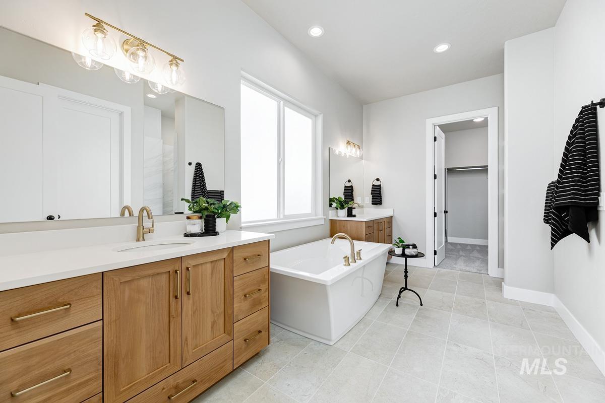 Full bath featuring vanity, a freestanding bath, recessed lighting, a spacious closet, and light tile patterned flooring