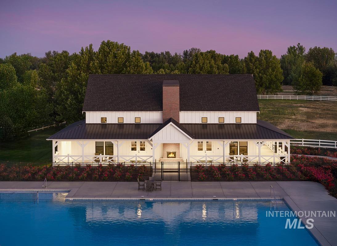 Rear view of property featuring a patio, a metal roof, an outdoor pool, and board and batten siding