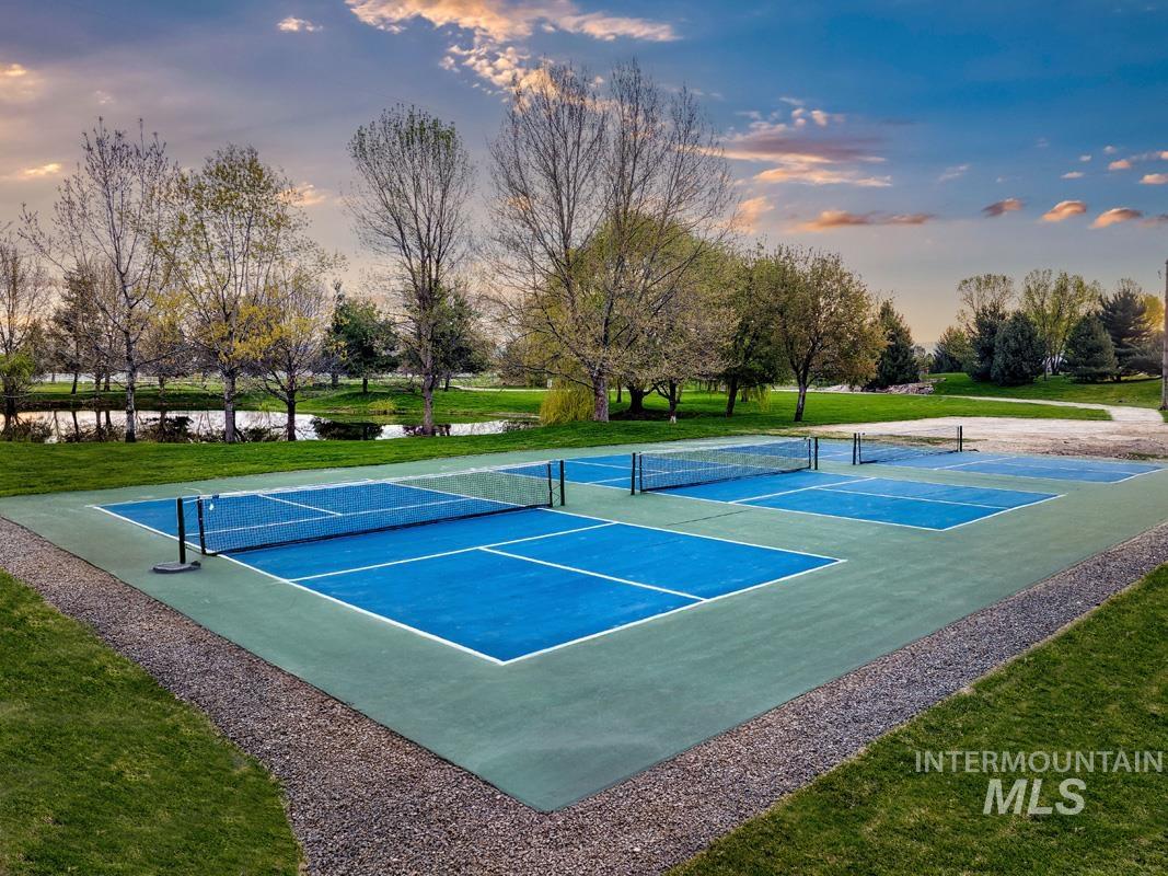 View of tennis court featuring a lawn and community basketball court
