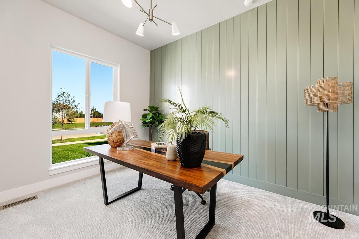 Carpeted office with a chandelier and wood walls