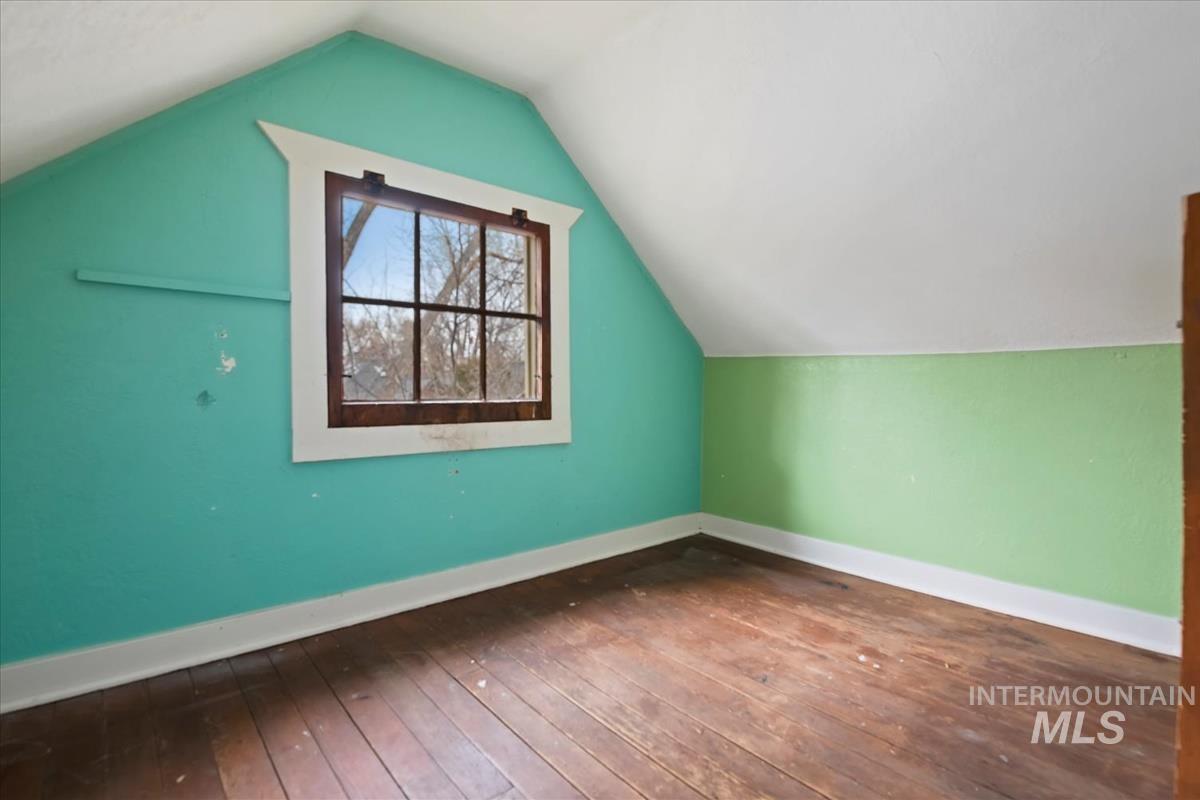 Additional living space with vaulted ceiling and dark wood-type flooring