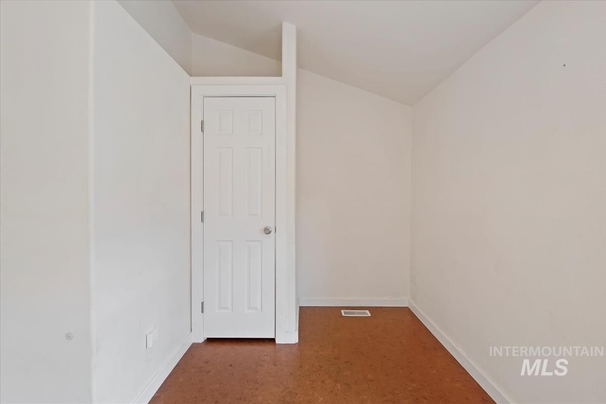 Unfurnished room featuring vaulted ceiling and baseboards