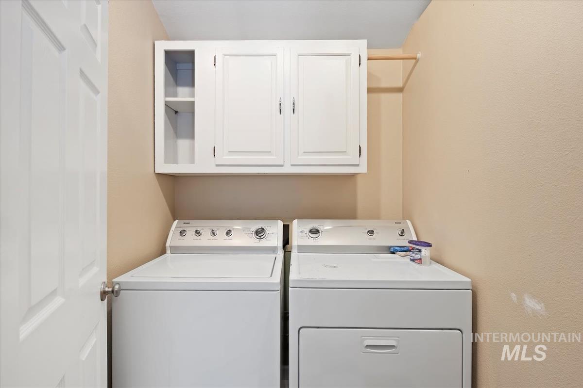 Washroom with cabinet space and washing machine and clothes dryer