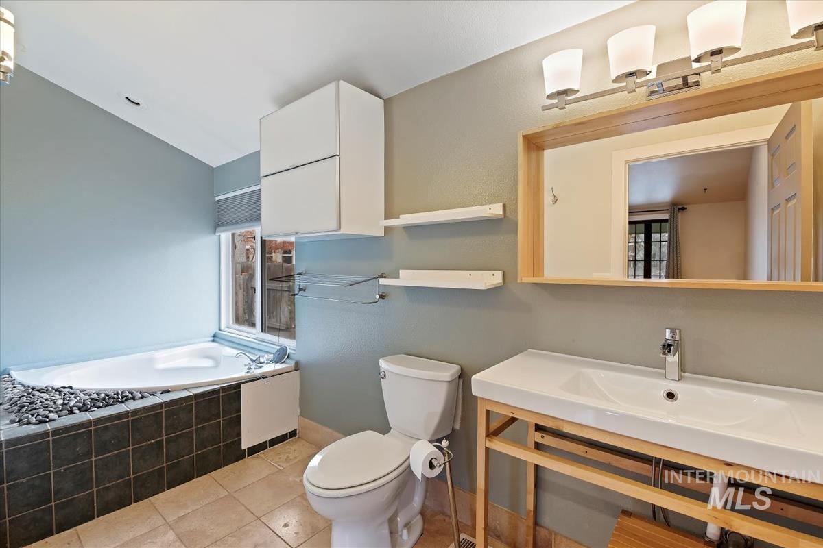 Full bathroom with a garden tub, light tile patterned flooring, and vaulted ceiling
