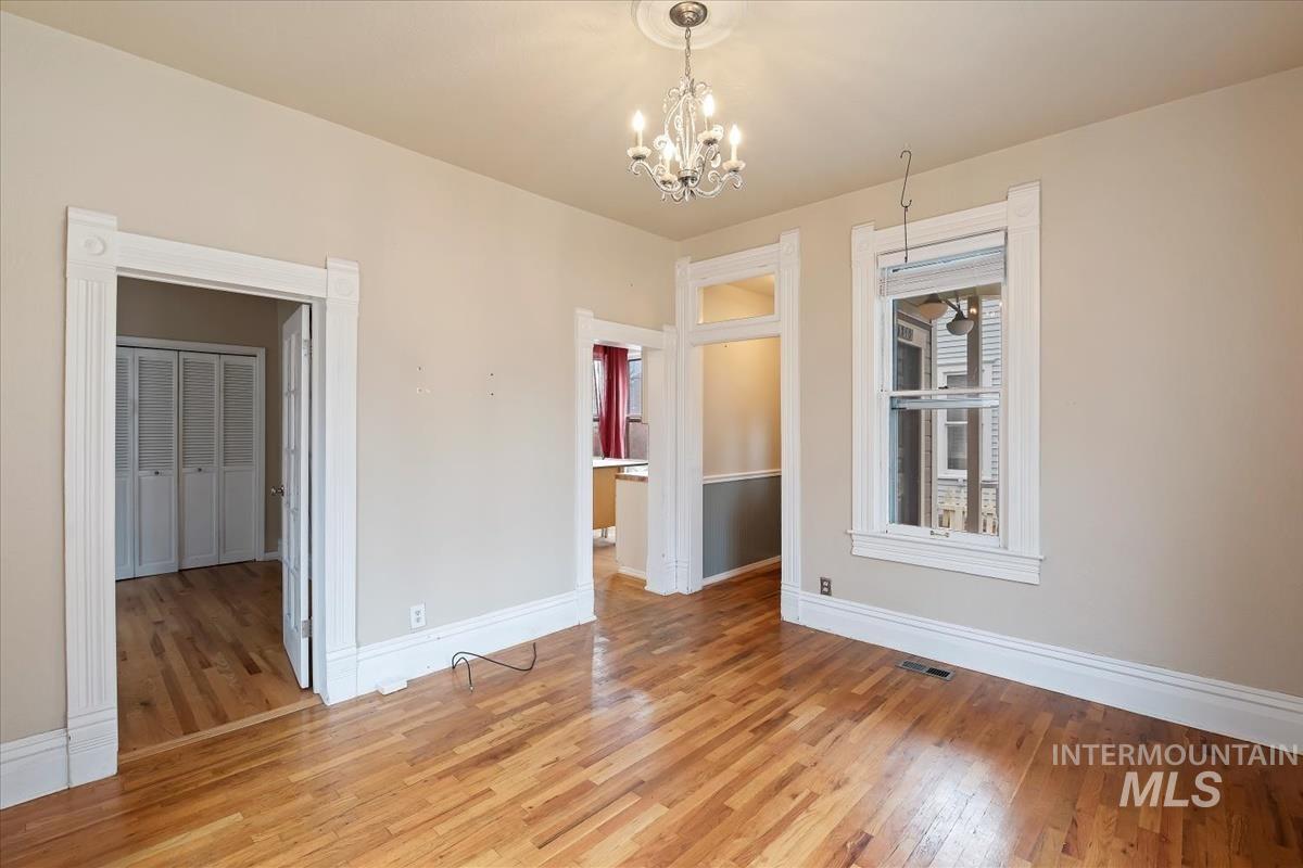 Empty room with hardwood / wood-style flooring and a chandelier
