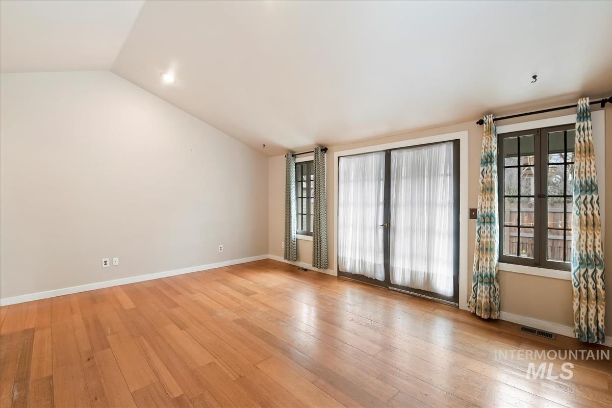 Empty room with light wood-style flooring and lofted ceiling
