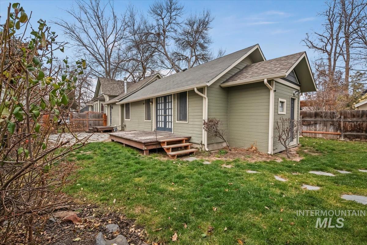 Rear view of property with a fenced backyard, a wooden deck, and a shingled roof