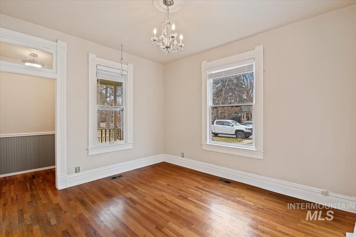 Unfurnished dining area featuring wood-type flooring and a chandelier