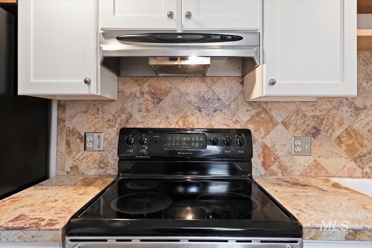 Kitchen featuring black appliances, light countertops, under cabinet range hood, and white cabinets