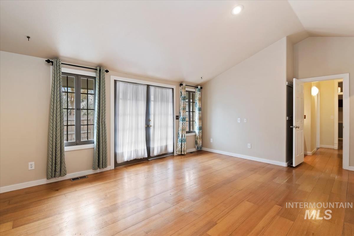 Spare room featuring light wood-style floors, plenty of natural light, and vaulted ceiling