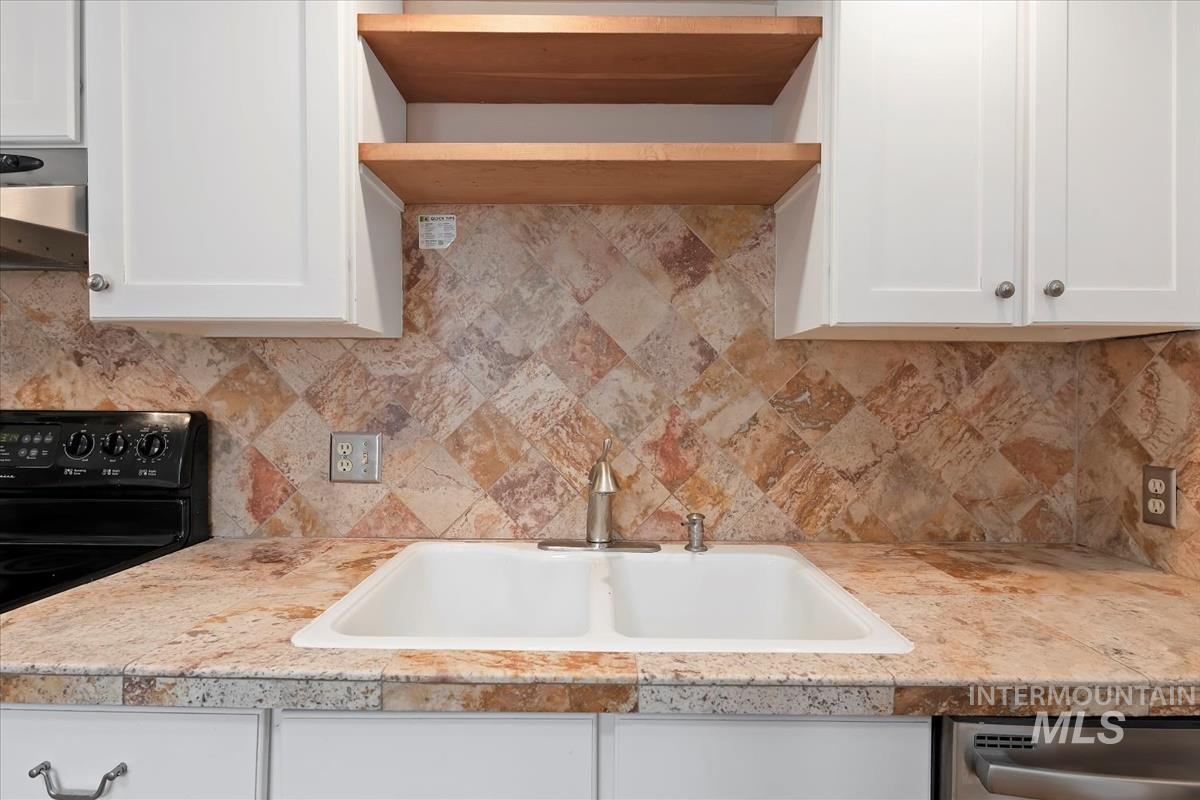 Kitchen with electric range, white cabinets, and exhaust hood