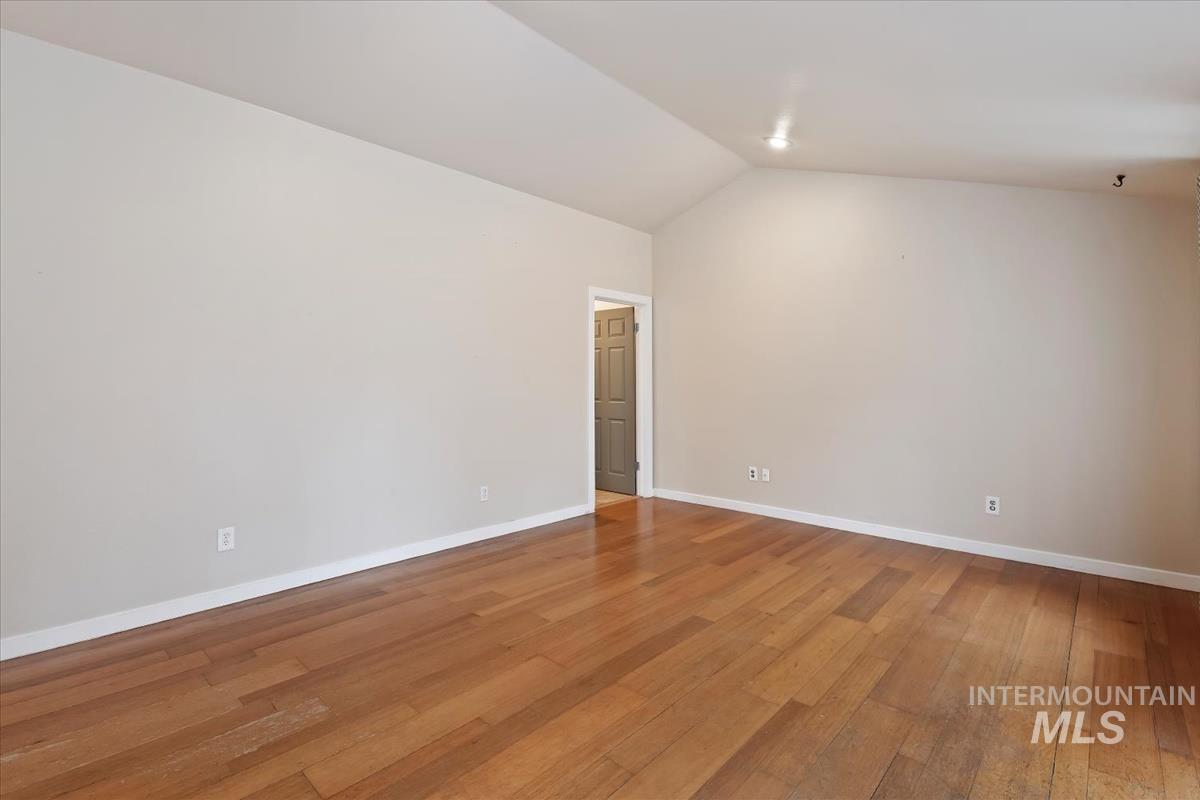 Unfurnished room with light wood-style flooring and lofted ceiling