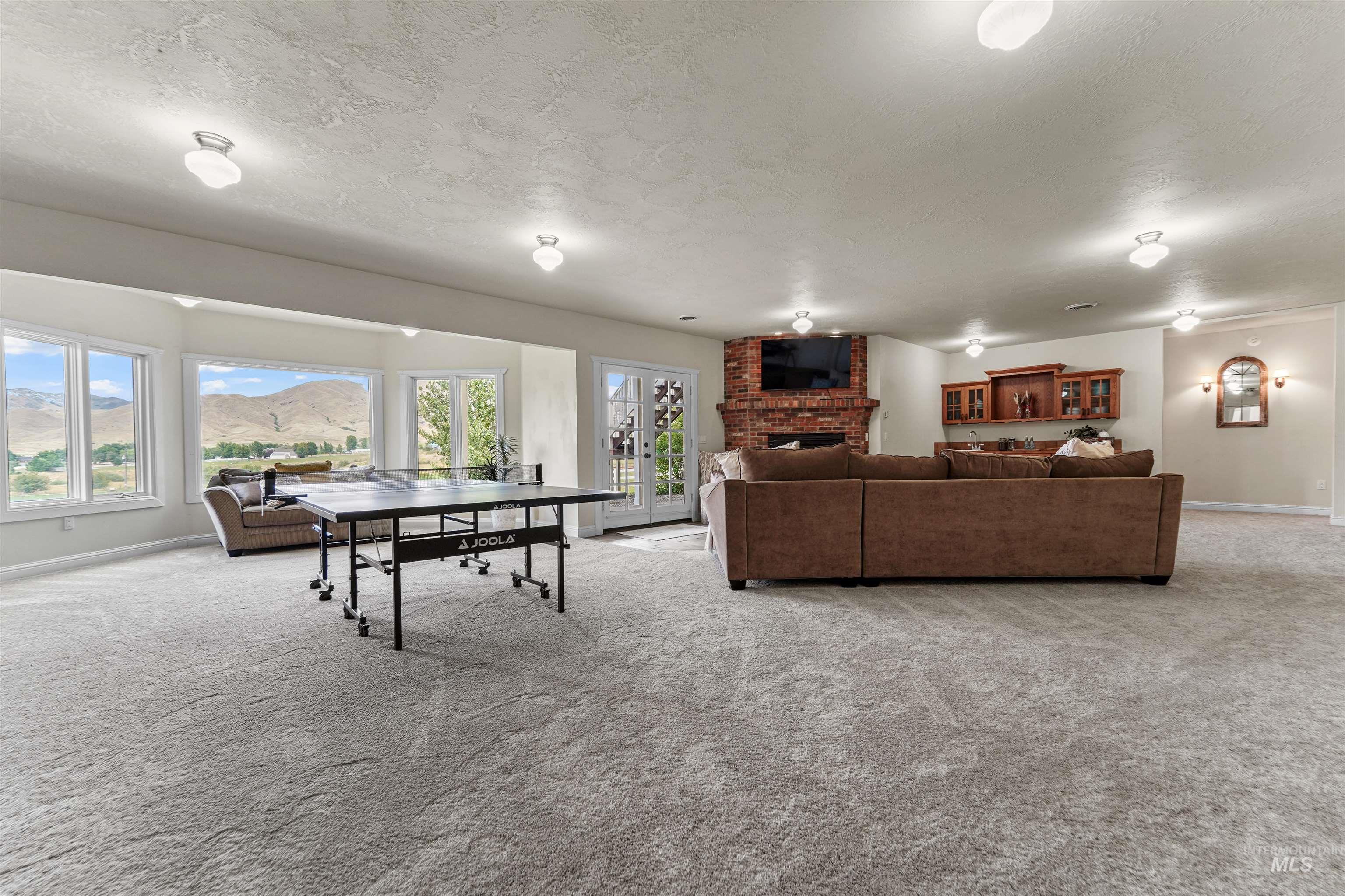 Living area featuring light colored carpet, a textured ceiling, a brick fireplace, and french doors