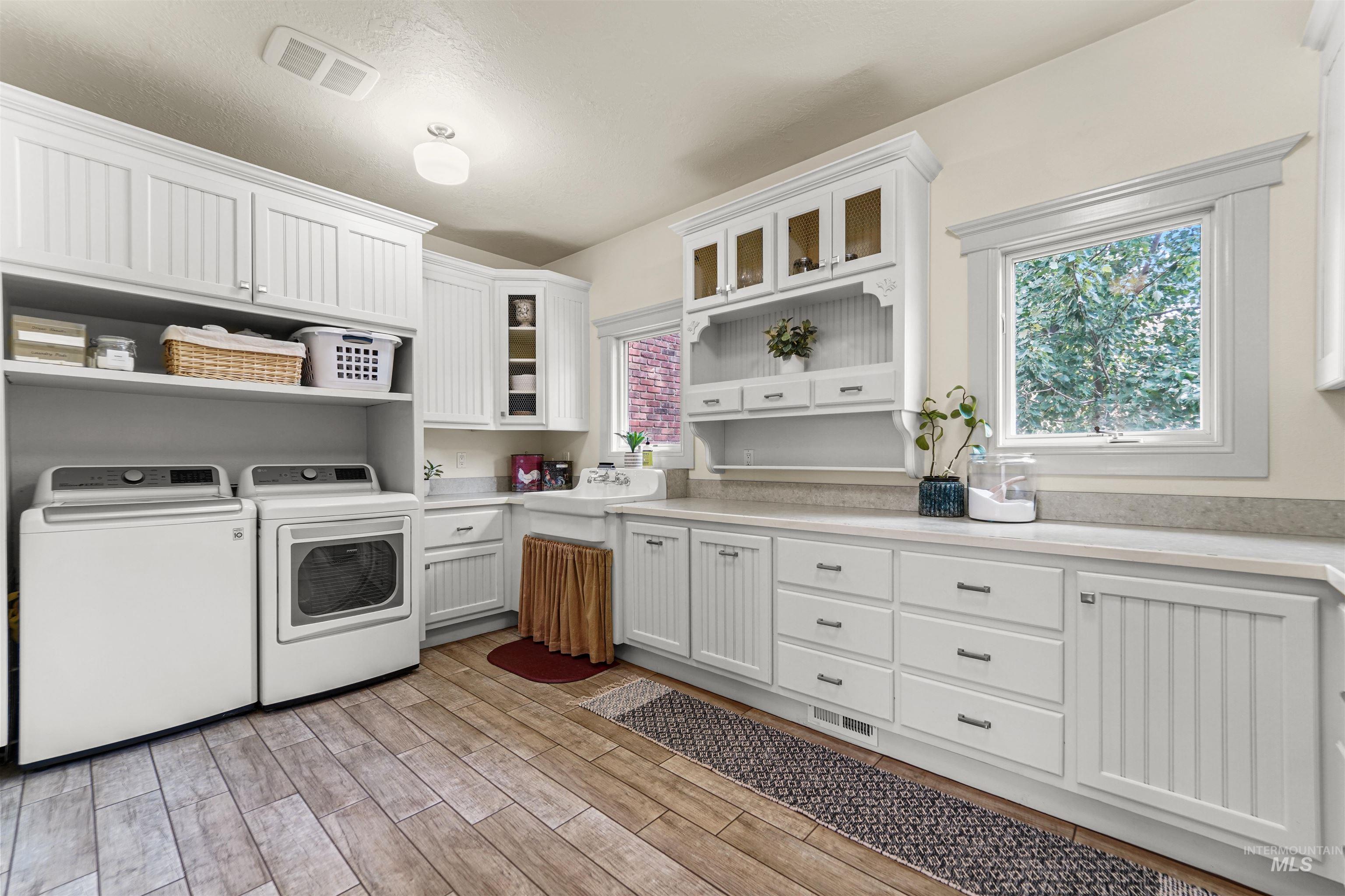 Laundry room featuring cabinet space, washer and dryer, plenty of natural light, and light wood-style floors