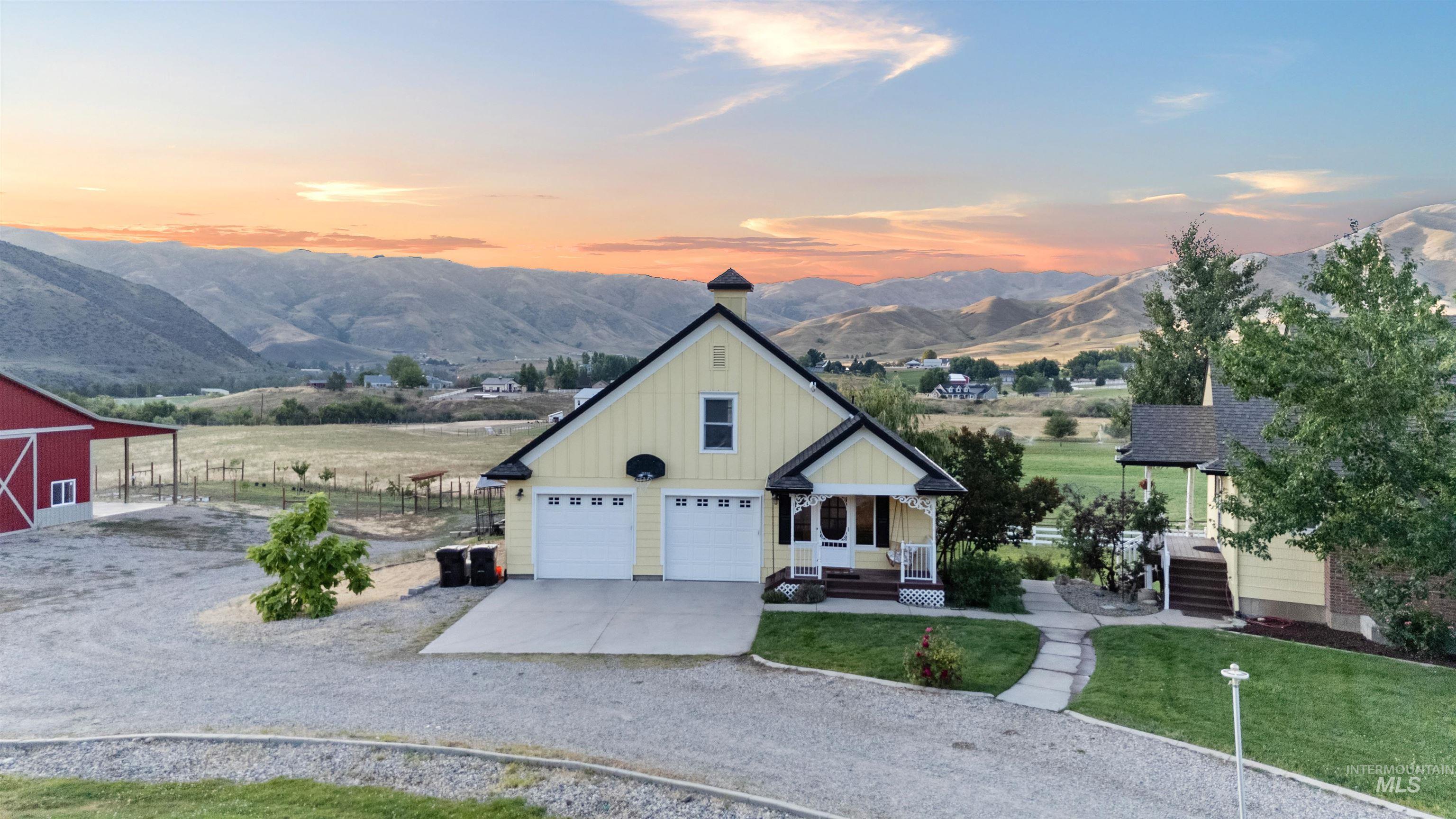 View of front of house featuring board and batten siding, concrete driveway, a mountain view, a chimney, and a garage