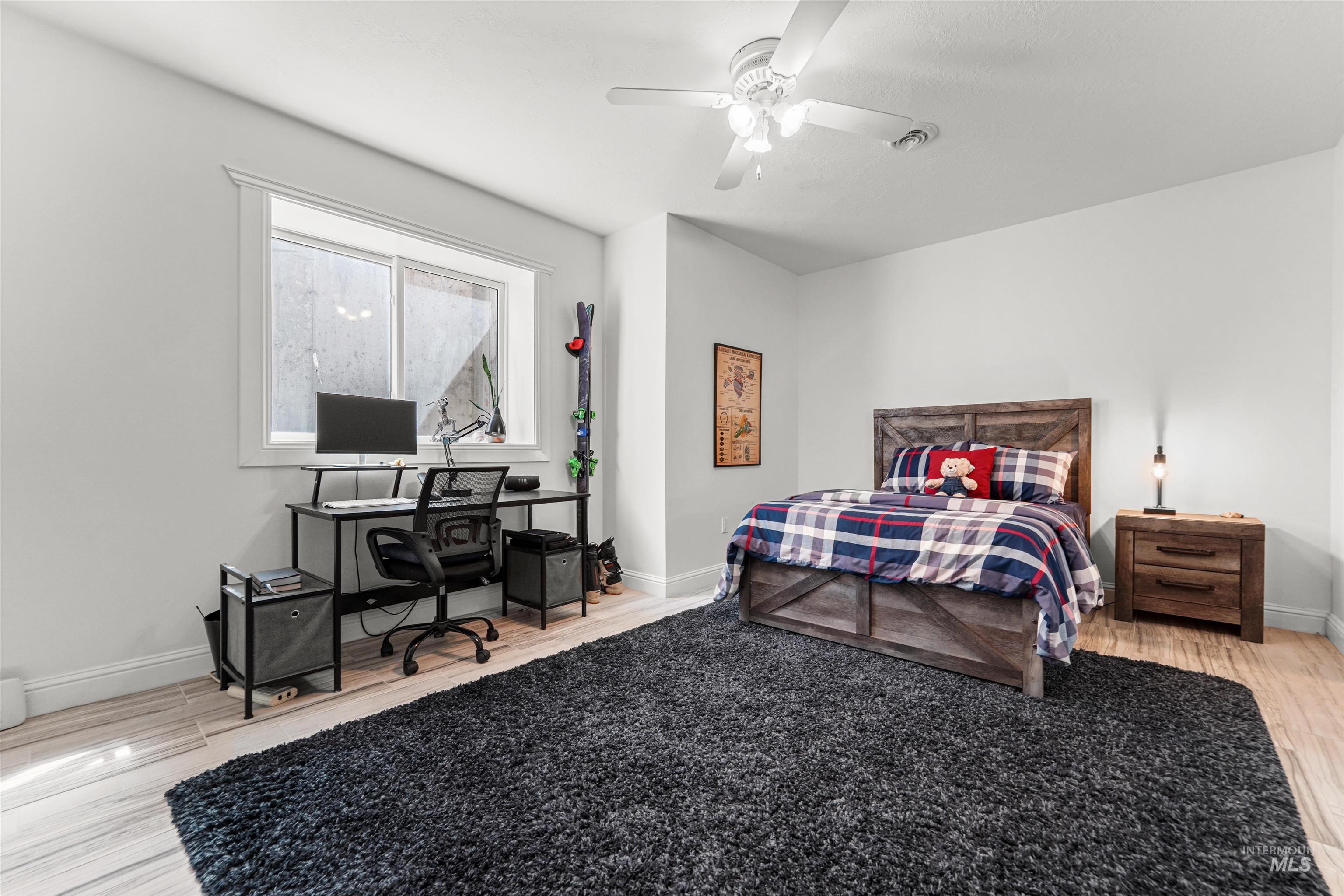 Bedroom featuring wood finished floors, an office area, and a ceiling fan