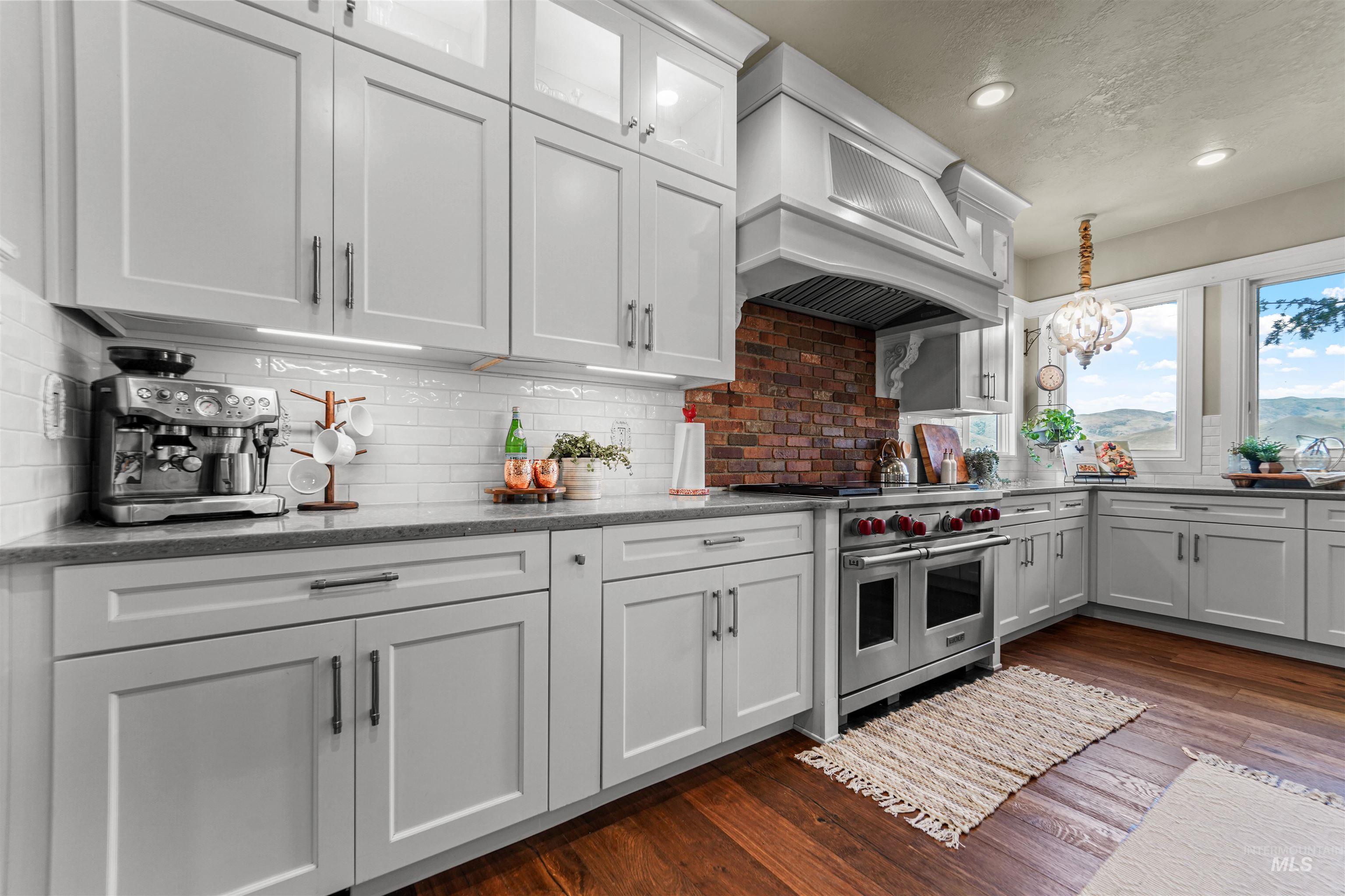Kitchen with decorative backsplash, double oven range, dark wood-style floors, premium range hood, and white cabinetry