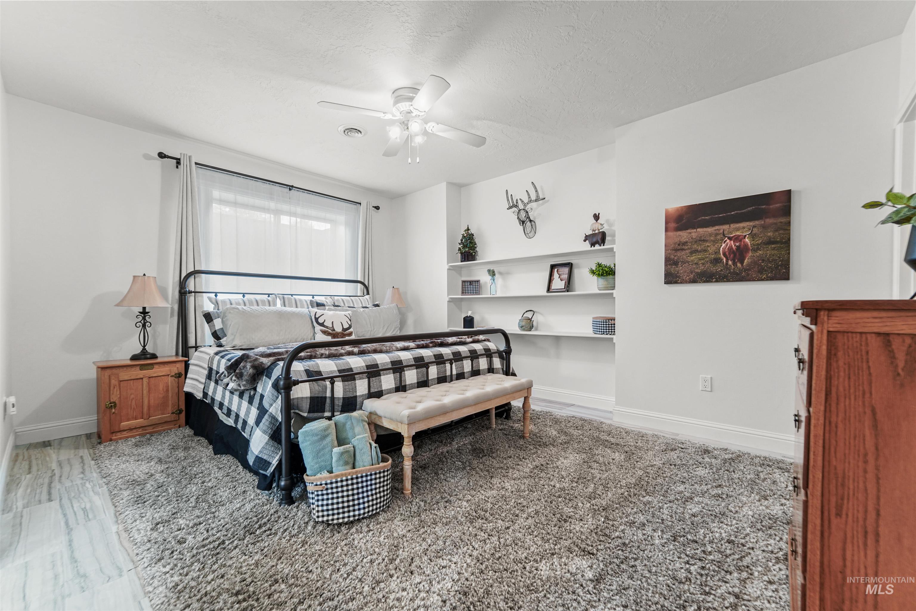Bedroom with a textured ceiling, ceiling fan, and light wood-type flooring