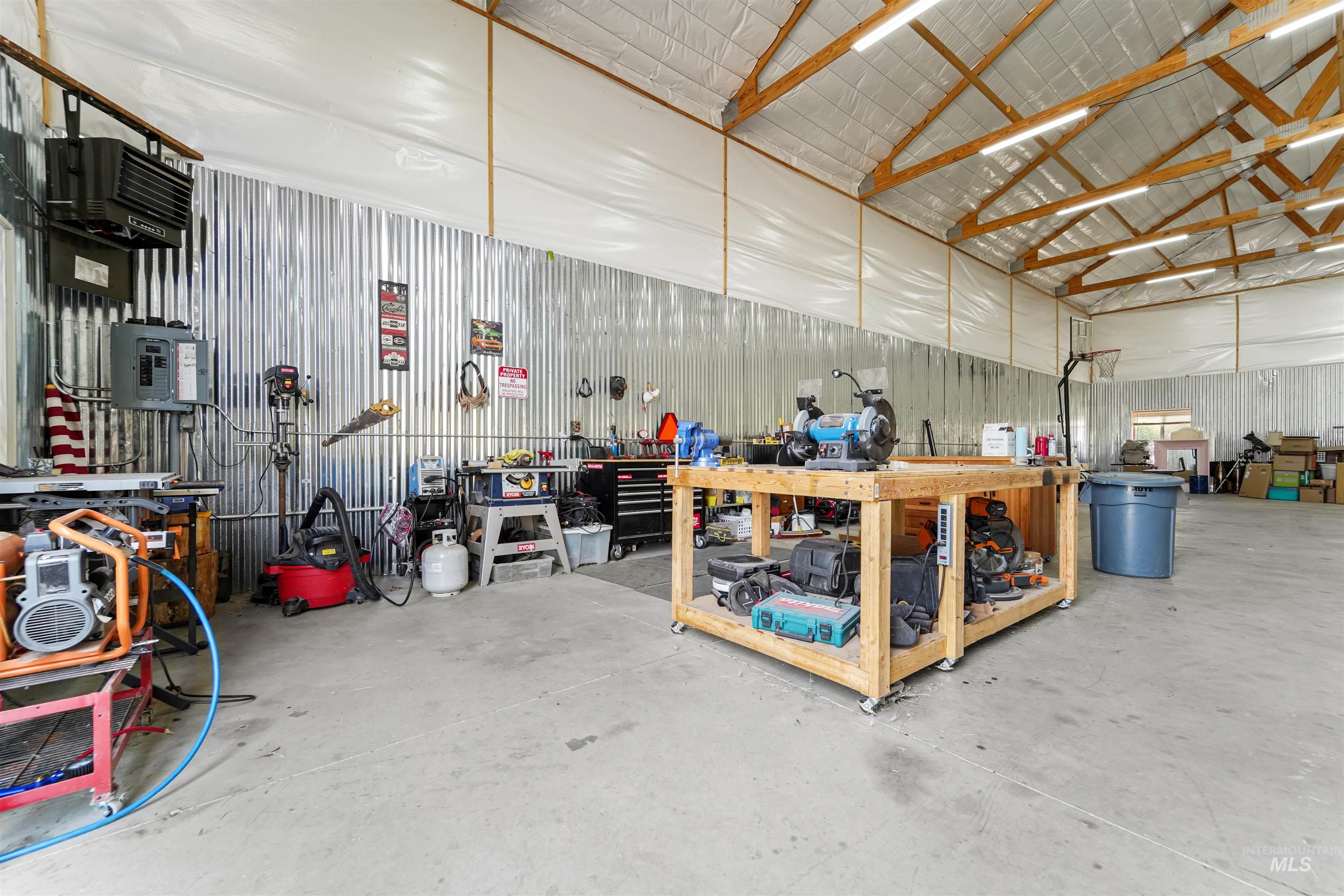 Garage with metal wall, a workshop area, a heating unit, and electric panel