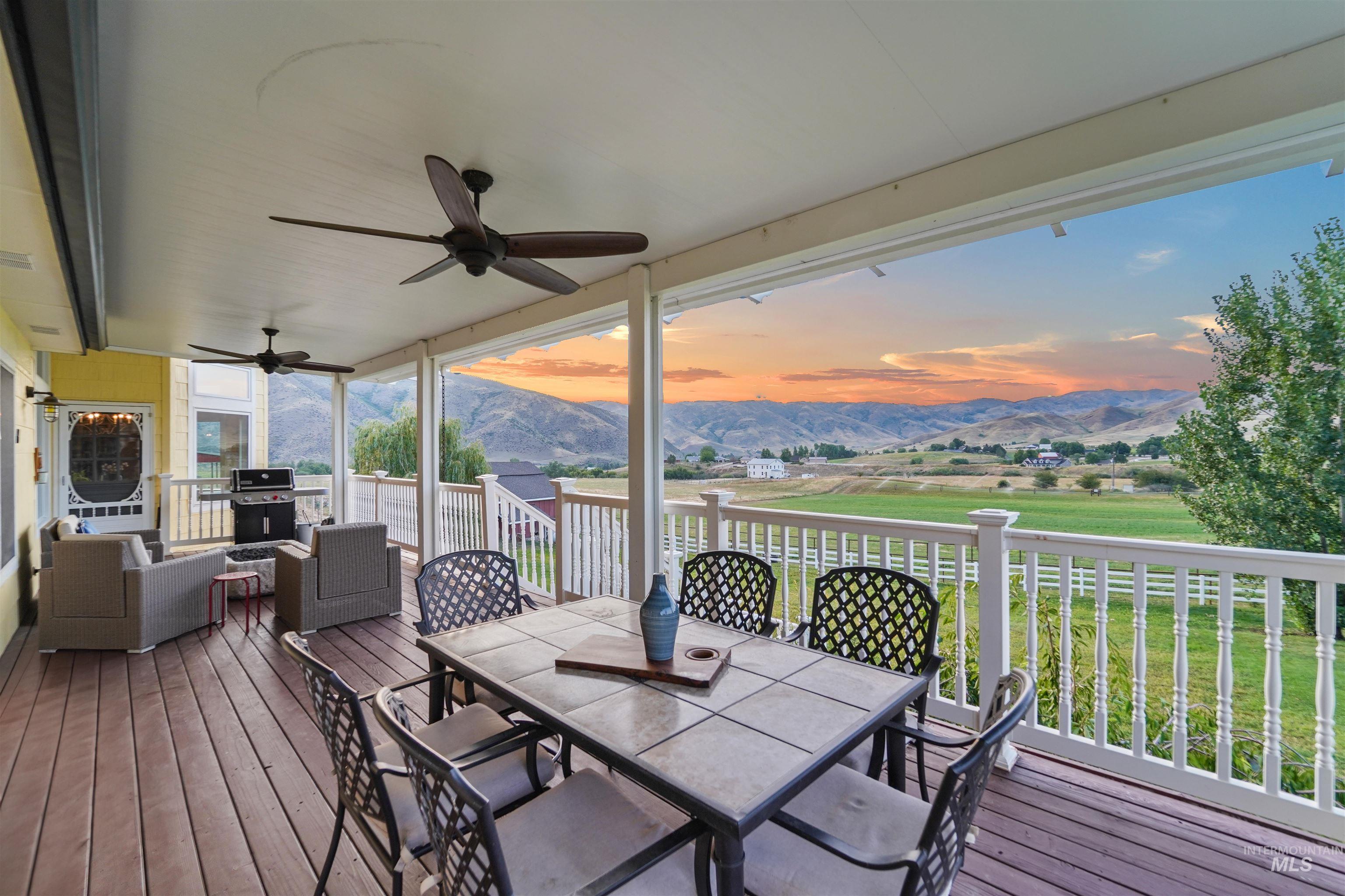 Wooden deck with outdoor dining space, a mountain view, a ceiling fan, and an outdoor living space