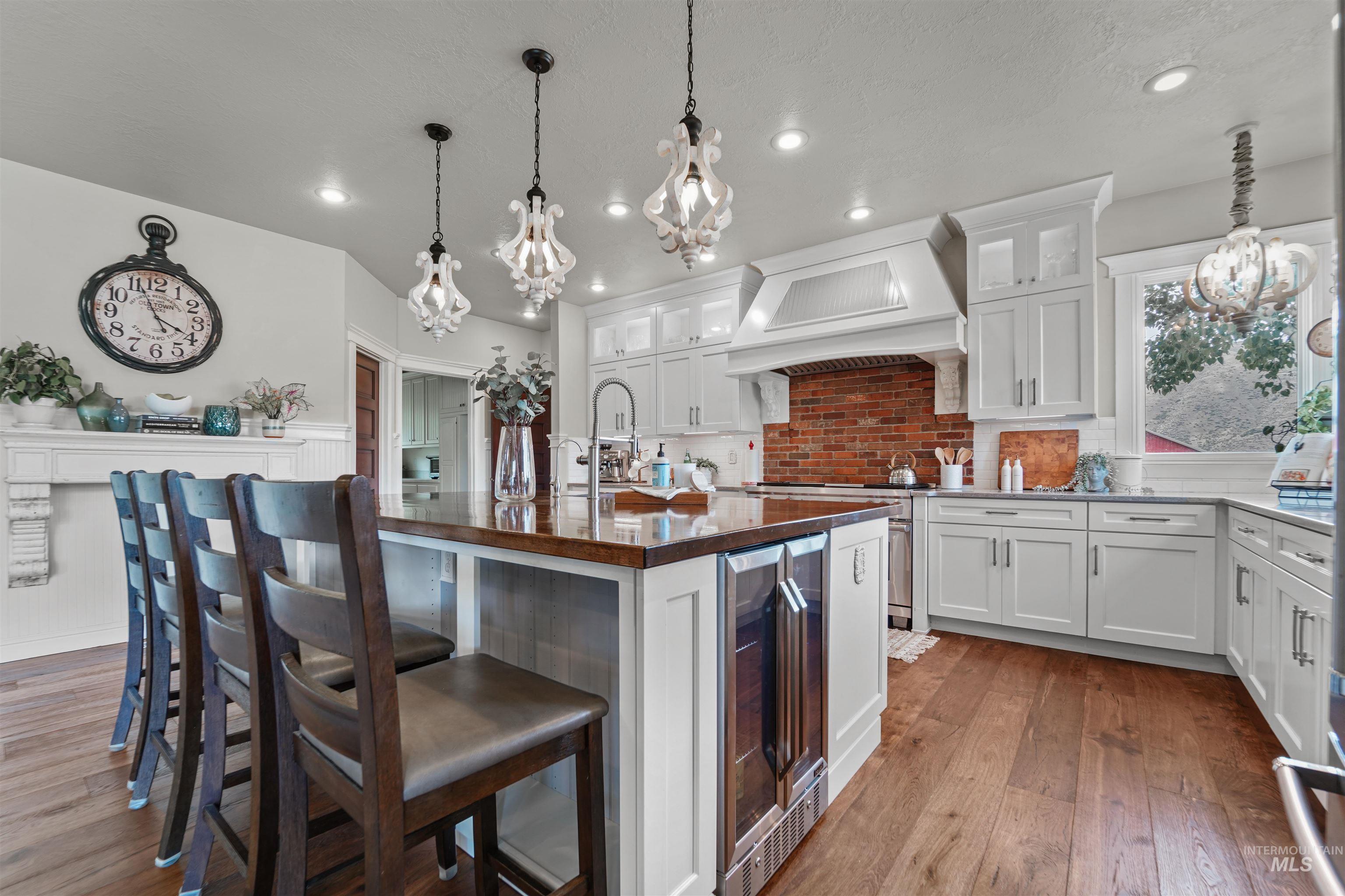 Kitchen with tasteful backsplash, butcher block counters, a chandelier, wood-type flooring, and recessed lighting