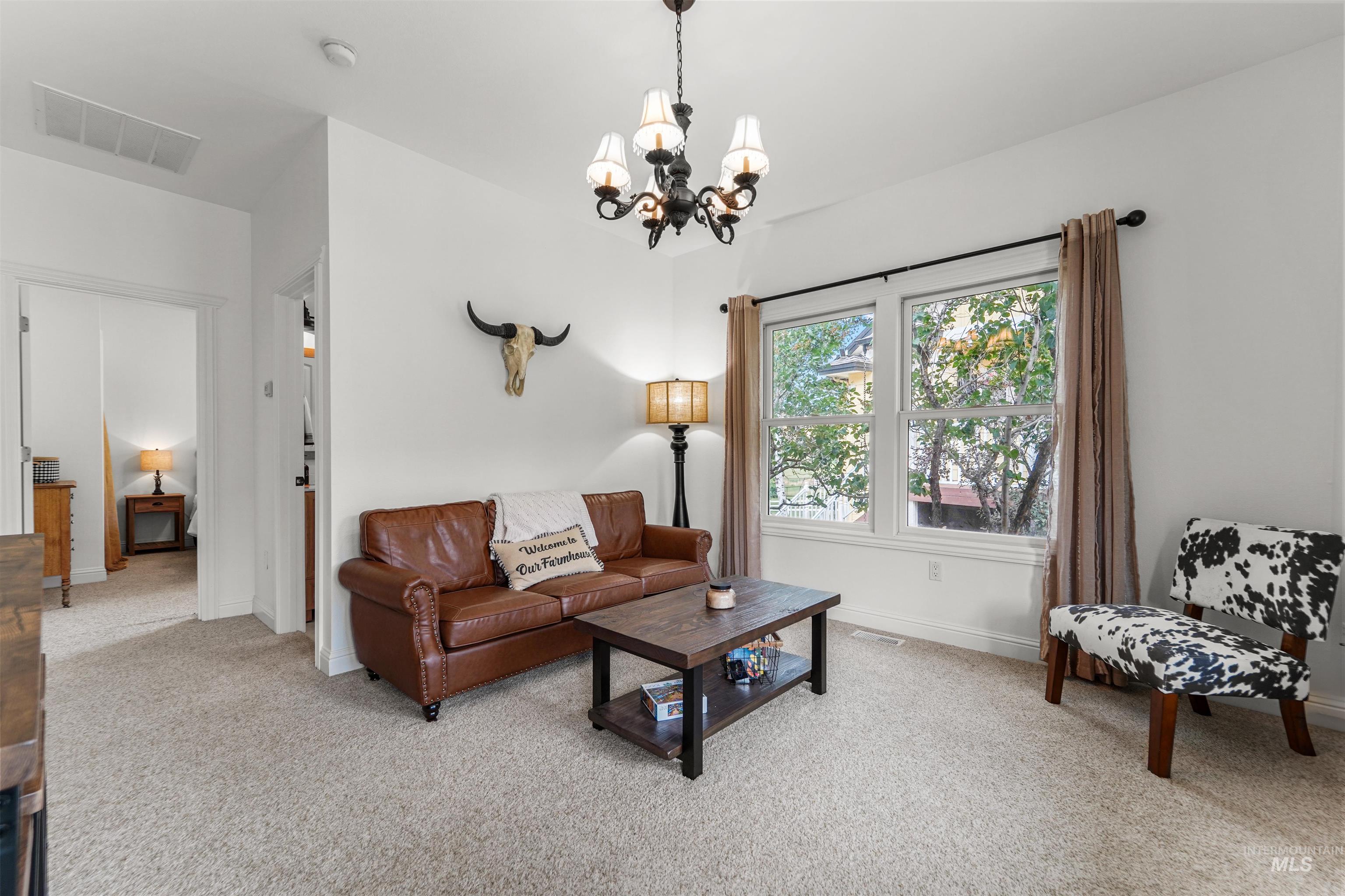 Living area featuring light carpet and a chandelier