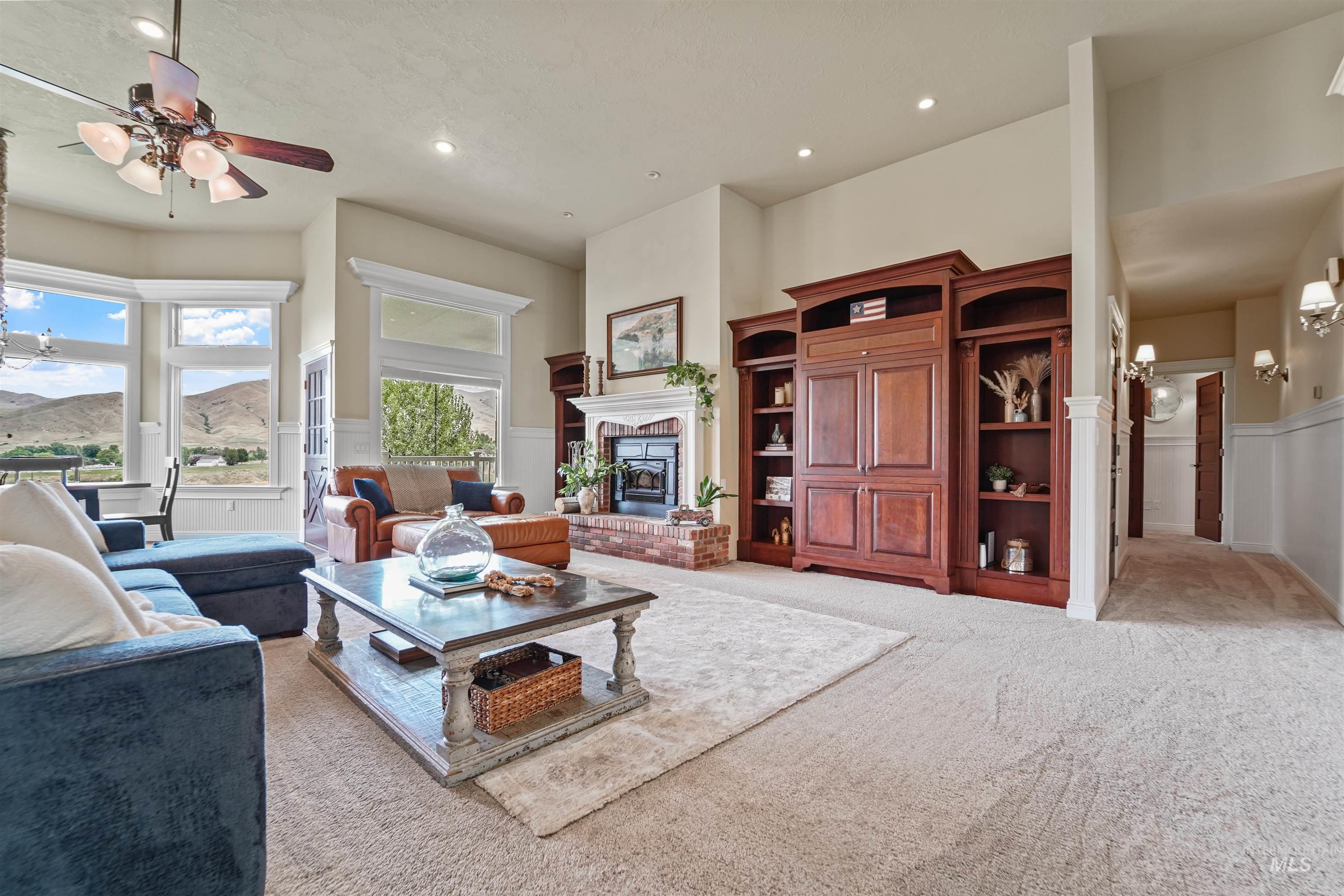 Living area with a wainscoted wall, a fireplace, a chandelier, light carpet, and recessed lighting