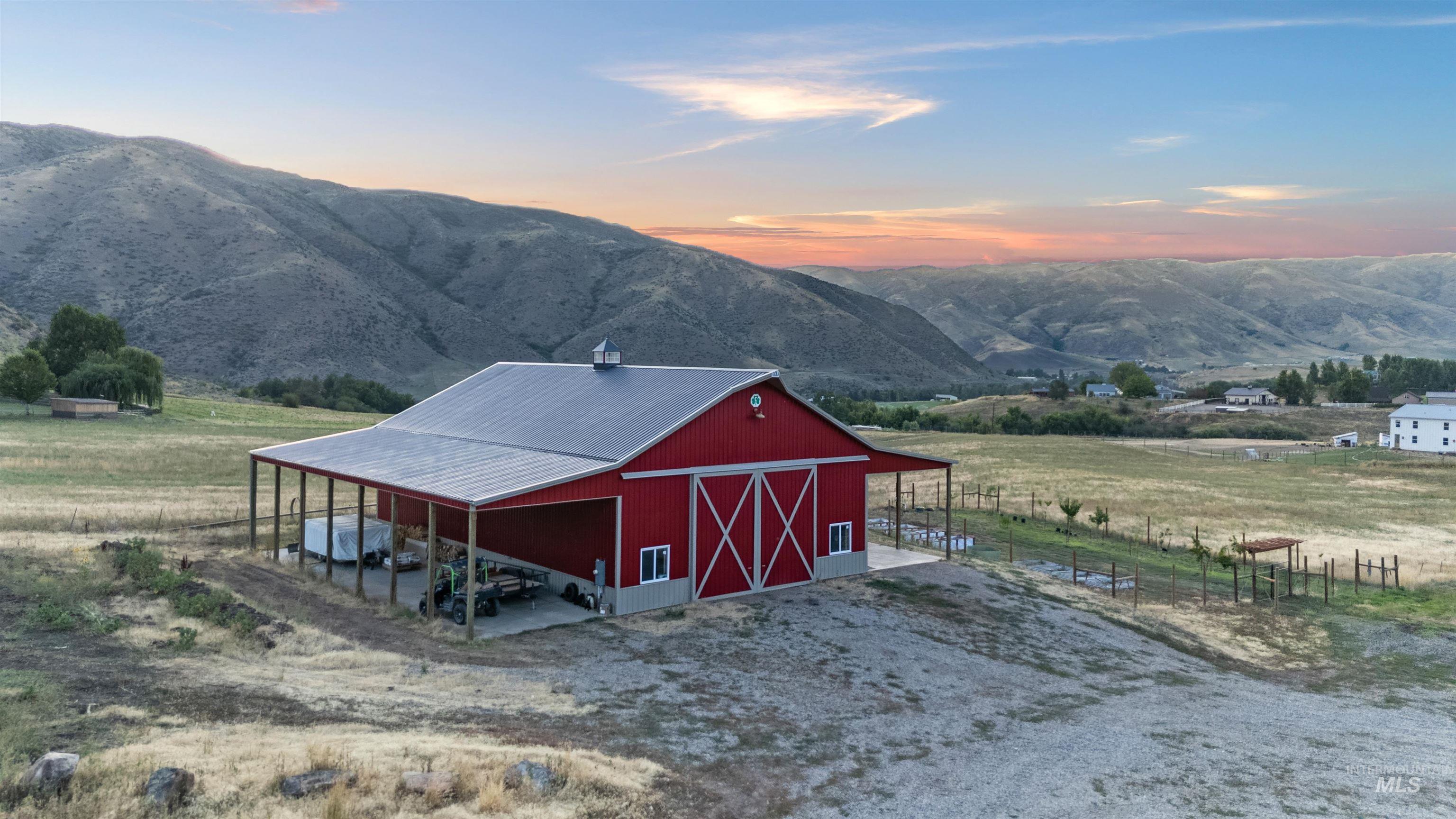 Outdoor structure at dusk featuring a mountain view, a barn, a view of countryside, and driveway