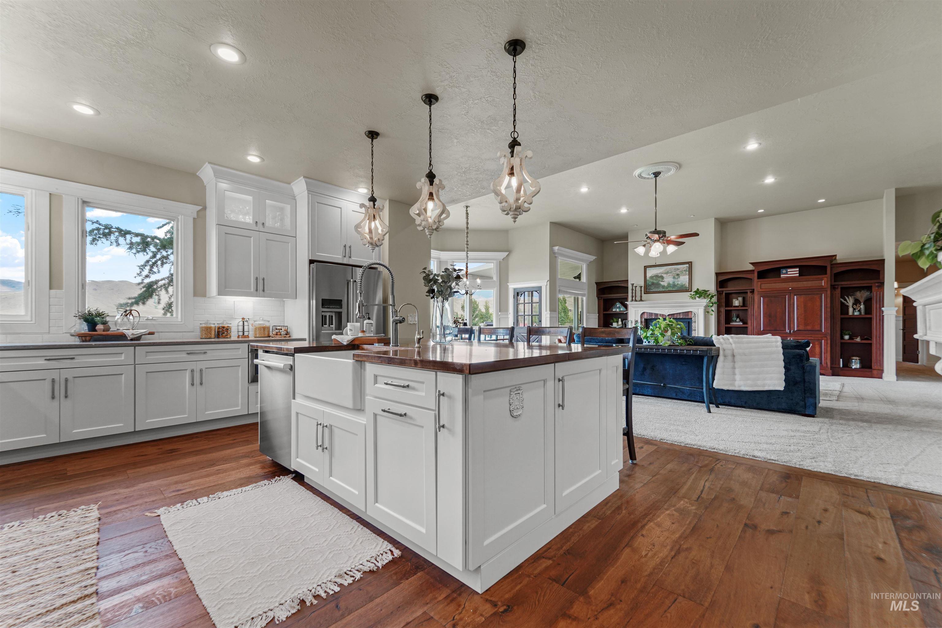 Kitchen with a fireplace, a ceiling fan, dark countertops, dark wood finished floors, and open floor plan