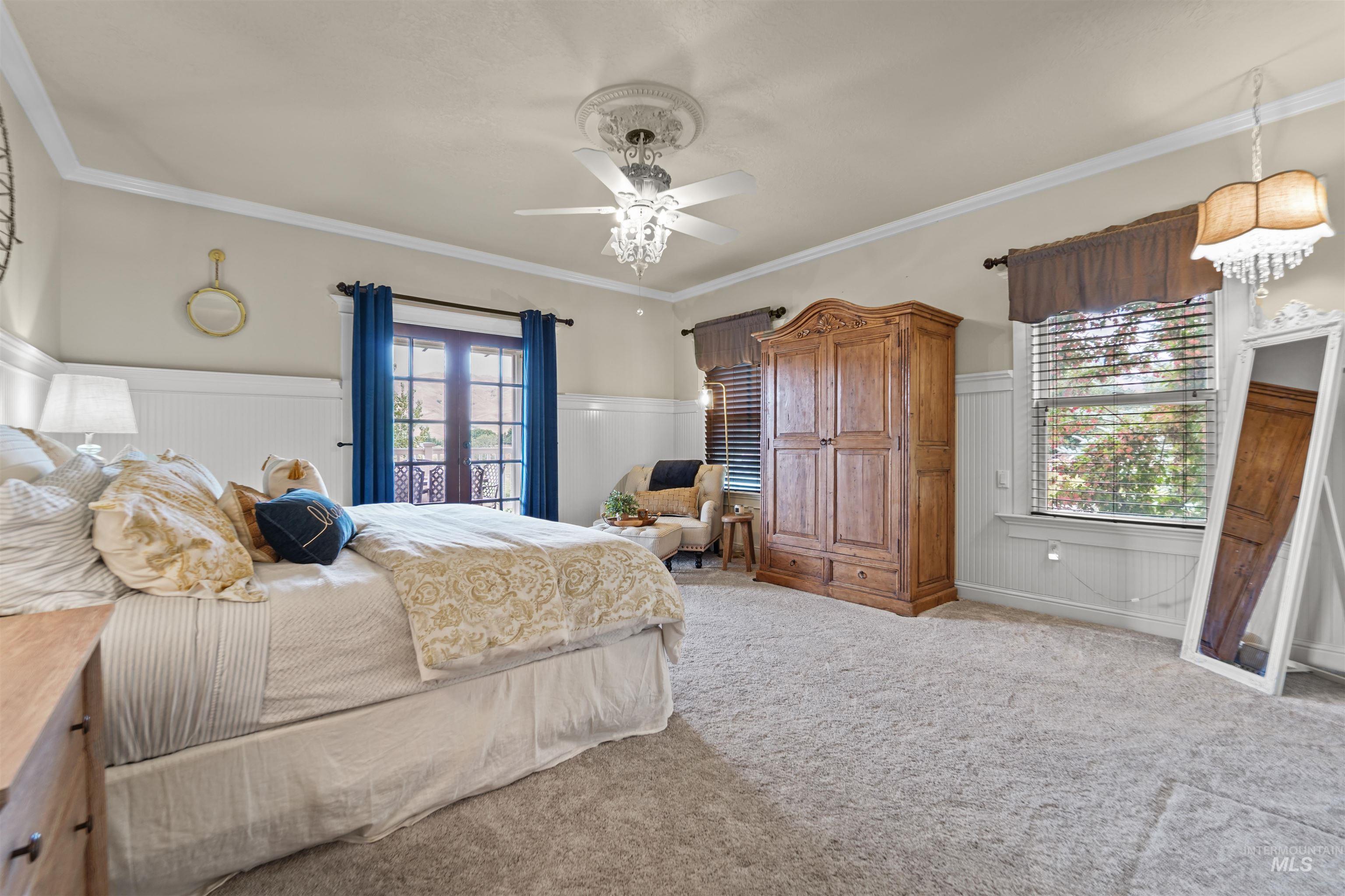 Bedroom with a wainscoted wall, crown molding, carpet, wooden walls, and a ceiling fan
