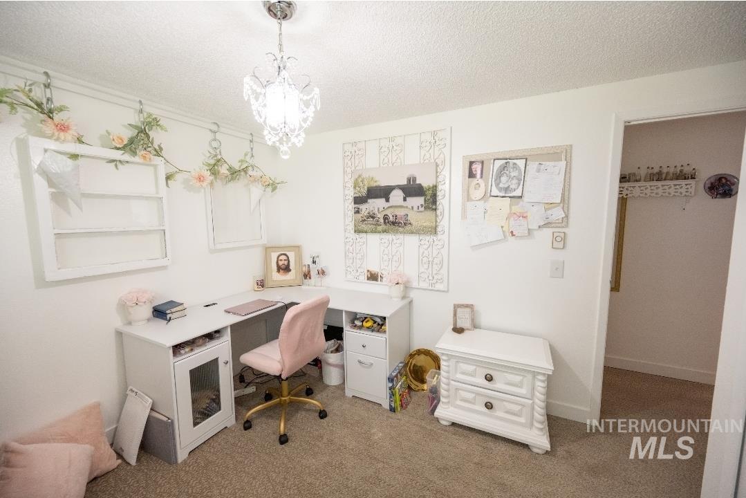 Office space featuring a textured ceiling, carpet, and a chandelier