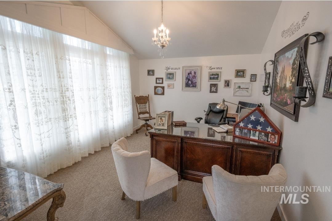 Carpeted office with vaulted ceiling and a chandelier