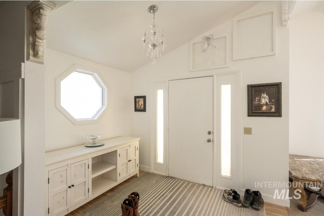 Entrance foyer with lofted ceiling, a chandelier, and carpet floors