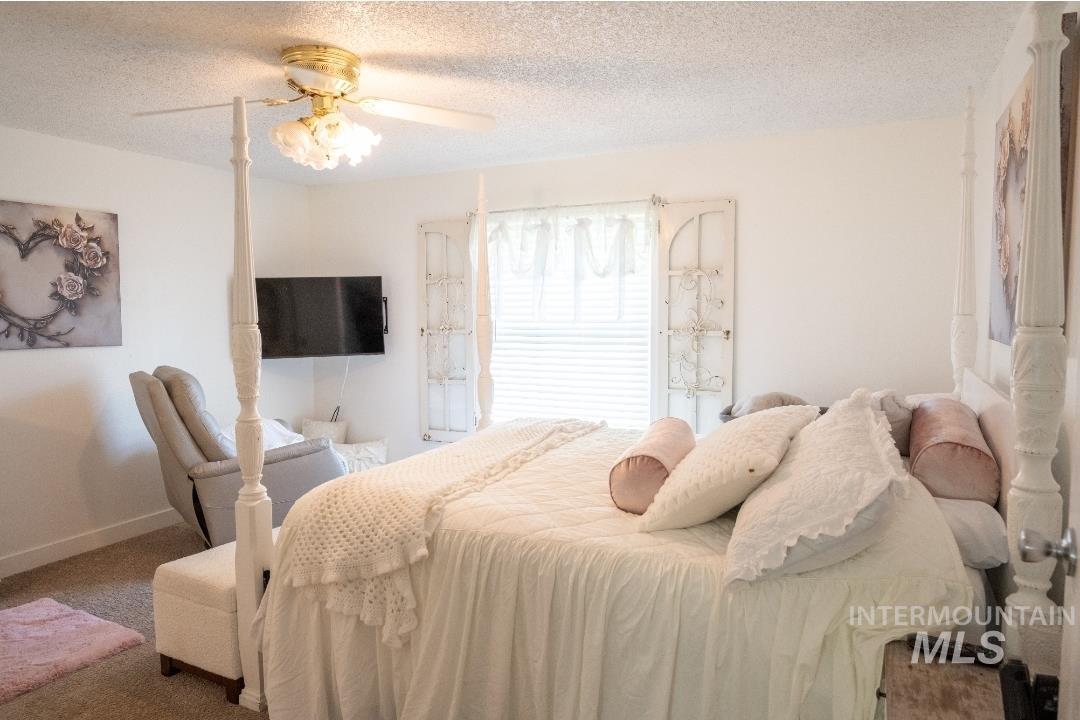 Bedroom featuring a textured ceiling, ceiling fan, and carpet floors